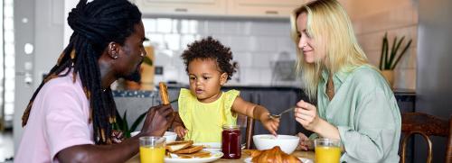 Man, woman and kid eating in the kitchen table
