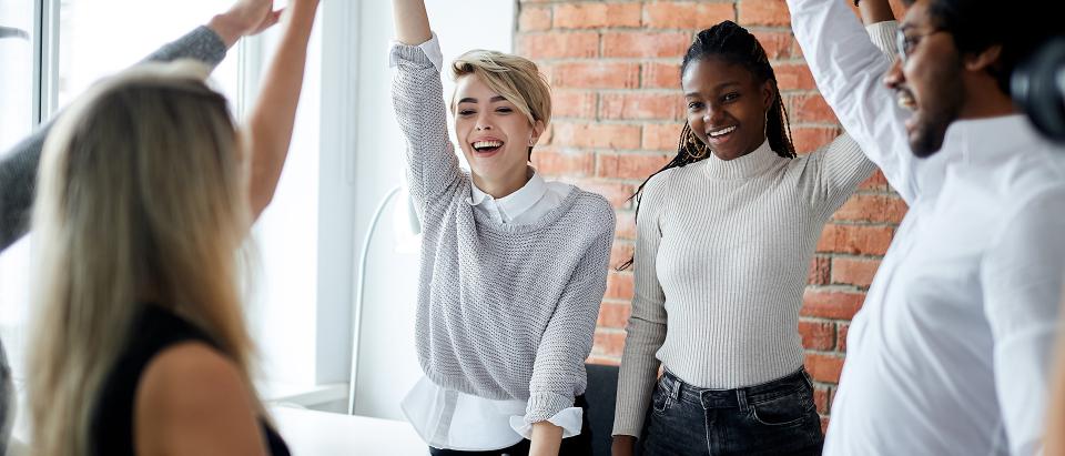 Cheerful mixed race office workers celebrating successful contract.