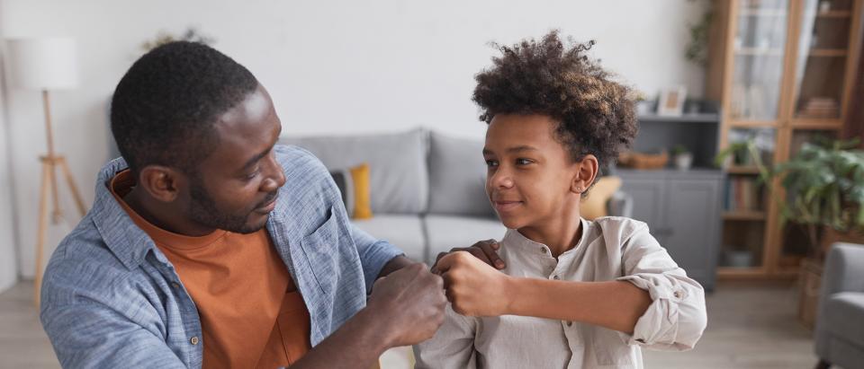 Man and teenager fist bumping after doing homework