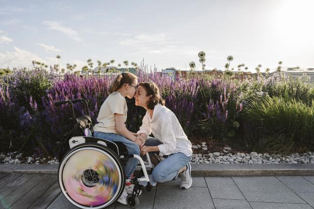 Girl in a wheelchair kissing woman in the nose on a lavender field