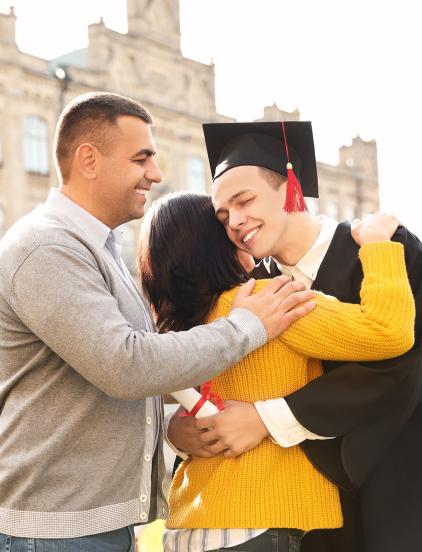 Man and woman hugging teenager graduating